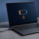 Windows laptop connected to a USB-C charger with a charging warning beside a dock