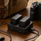 USB-C camera battery charger with two batteries beside a camera and travel bag