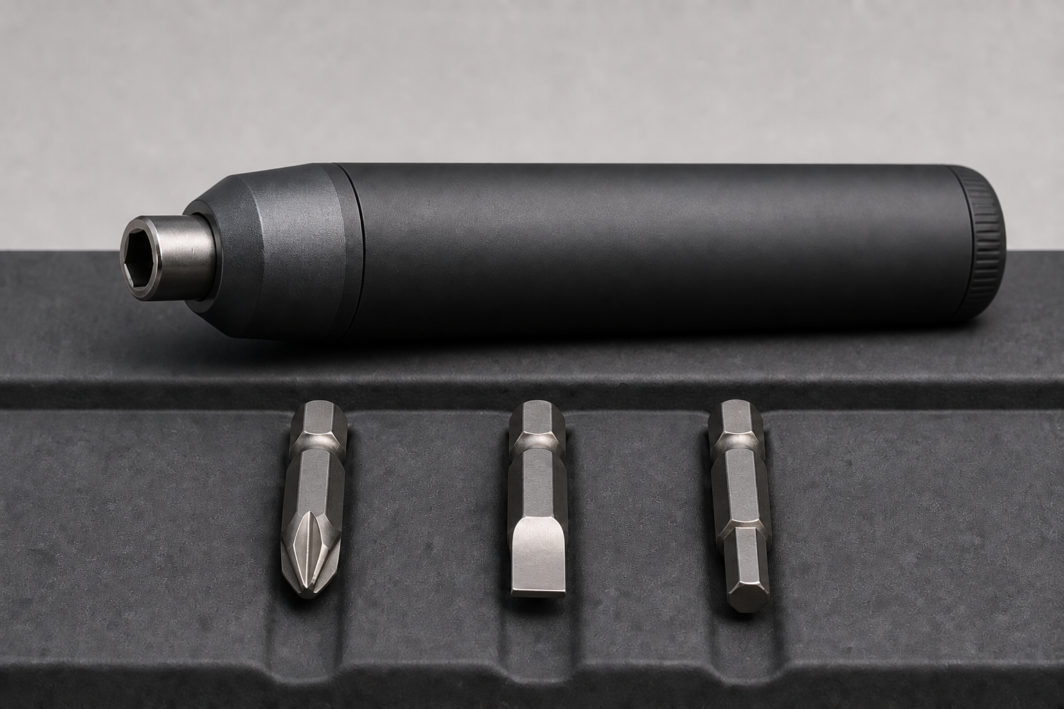 Unbranded electric screwdriver beside three distinct driver bits: Phillips, slotted, and hex.